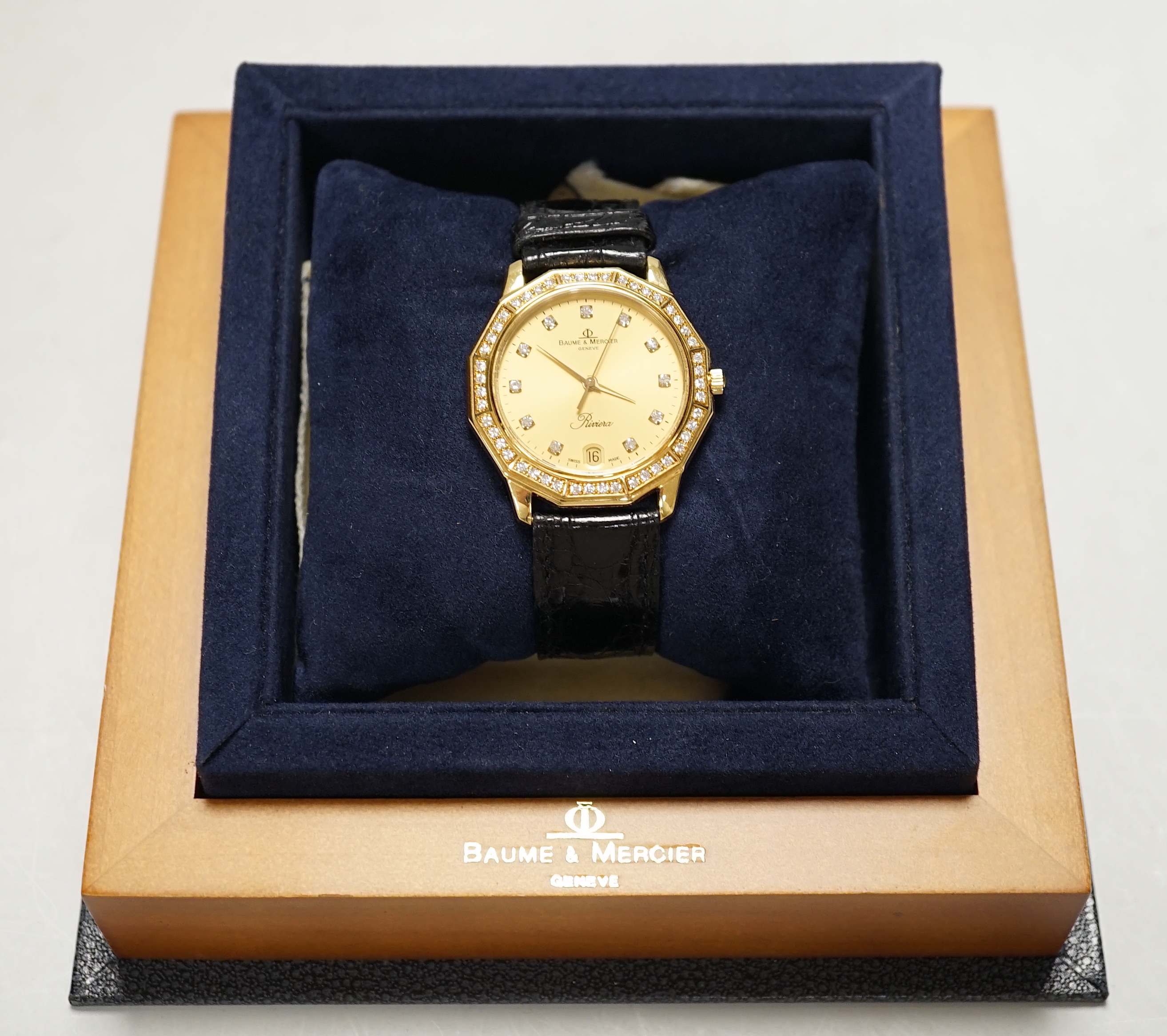 A gentleman's modern 18ct gold and diamond set Baume & Mercier Riviera quartz wrist watch, with do-decagonal case, on a Baume & Mercier leather strap, case diameter 34mm, with box and papers.